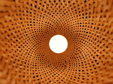 Detaylı desenlerle örülmüş saman dekoruyla çevrili bir lambanın makro görüntüsü.