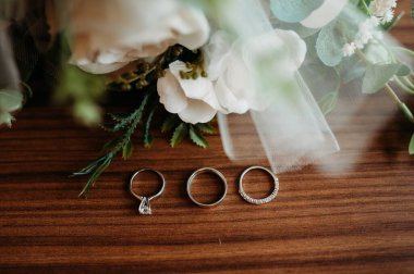 Alyanslar ahşap bir masanın üzerinde gelin buketi ile.