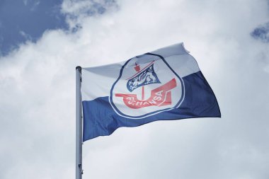 FC Hansa Rostock bayrağı rüzgarda dalgalanıyor. Arkasında bulutlu bir gökyüzü var..