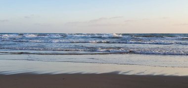 Kumlu sahil üzerinde dalgalı deniz suyunun panoramik görüntüsü