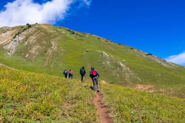 Güneşli bir günde mavi gökyüzünün altındaki bir dağa tırmanan yürüyüşçülerin yakın çekimi.