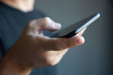 Akıllı telefonu tutan bir elin yakın çekimi.