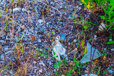 Kayalık bir zemine yerleştirilmiş kullanılmış bir tıbbi maskenin yakın çekimi.