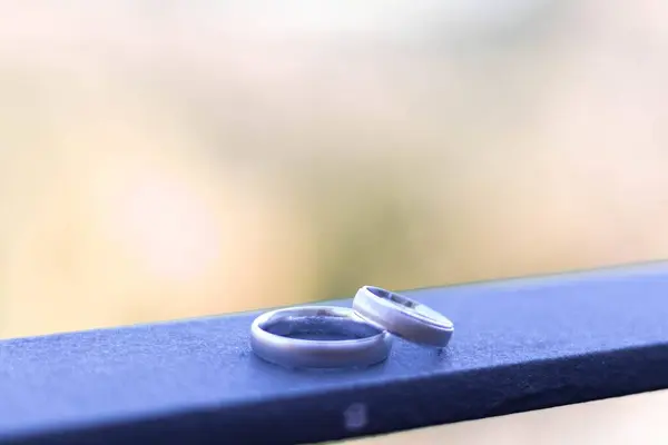 Egy Közeli Kép Két Jegygyűrűről Egy Kék Felületen Homályos Háttérrel — Stock Fotó