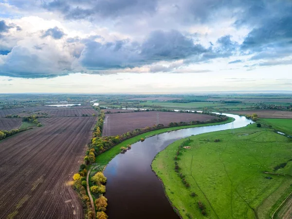 曇りの空を背景に農村部の農地に囲まれた川の空中風景 — ストック写真