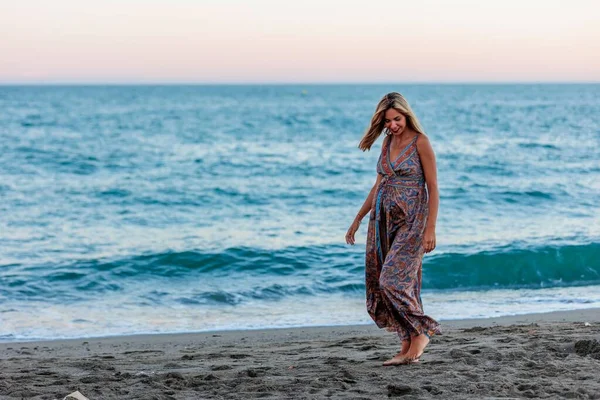 一个穿着裙子在海滨散步的年轻快乐的孕妇 — 图库照片
