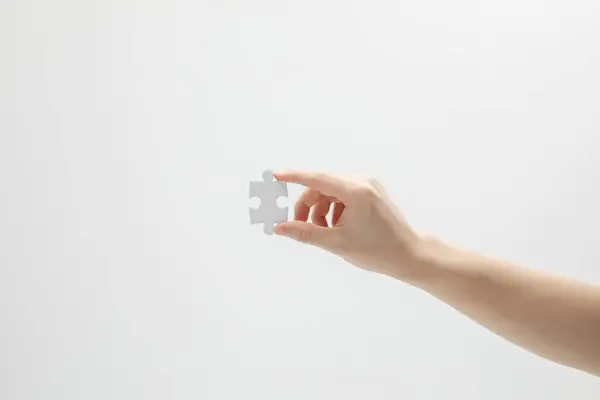 stock image A closeup shot of a hand holding a puzzle piece in front of a white background with copy space