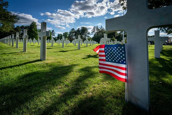 ノルマンディーの戦争墓地で殺された兵士の墓石に立っているアメリカの旗 — ストック写真