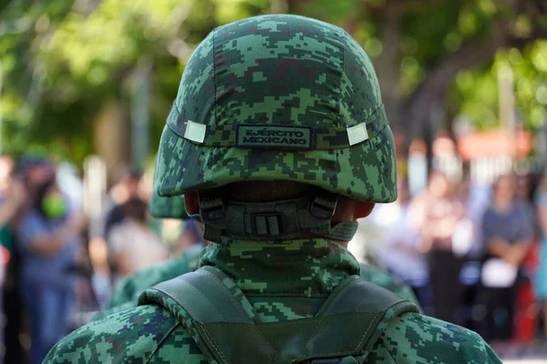 A closeup of a Mexican soldier in combat helmet and camouflage during a civic act on Mexico\'s flag day
