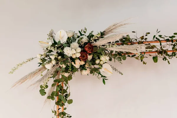 在白色的墙上用鲜花装饰的一个漂亮的婚礼装饰品的特写 — 图库照片