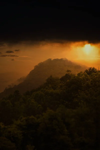 在多雾 多雨的天气里 背景是落日的天空 俯瞰着一座森林覆盖的山 — 图库照片