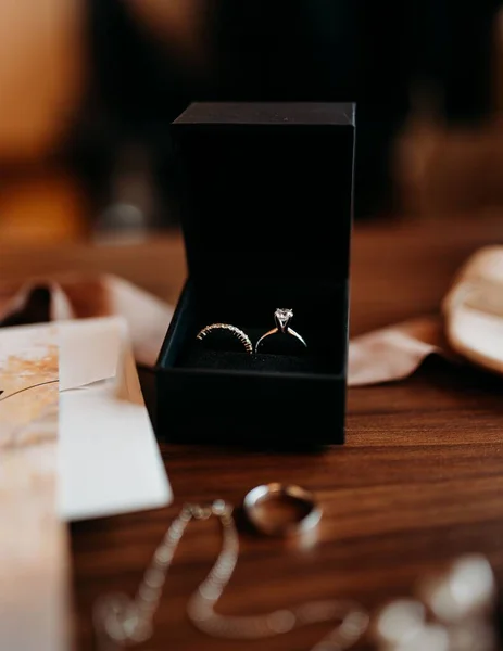 Egy Függőleges Felvétel Jegygyűrűkről Egy Fából Készült Asztalon Menyasszonyi Csokorral — Stock Fotó
