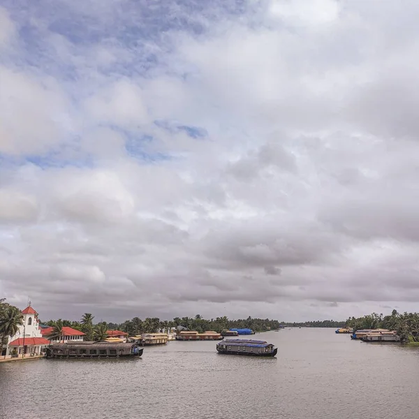 一条宽阔而平静的河 在多云的天空下 船在水面上与小房子一起游动 — 图库照片