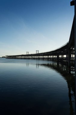İspanya 'nın Huelva kentindeki Rio Tinto rıhtımının dikey manzaralı Atlantik okyanusu boyunca mavi gökyüzüne karşı