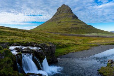 İzlanda 'da ipeksi uzun bir şelalenin çerçevelediği Kirkjufell Dağı' nın güzel manzarası.