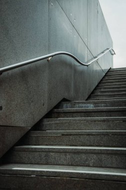 Dışarıdaki merdivenlerin dikey görüntüsü. Açık gökyüzü olan metal bir tırabzan.