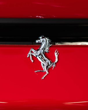 Parlak kırmızı bir araç iskeletinde Ferrari krom at rozetinin dikey yakın çekimi.