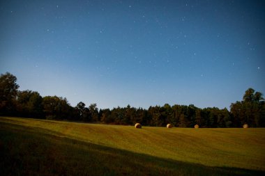 Yıldızlı bir gecede yuvarlak balyalarla dolu bir tarla