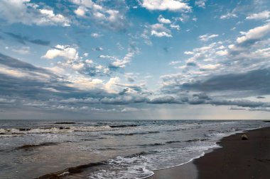 Dramatik bir gökyüzünün altında deniz dalgaları olan güzel bir deniz manzarası.