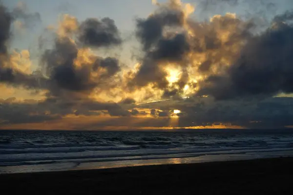 背景には曇り空のビーチで美しい夕日 — ストック写真