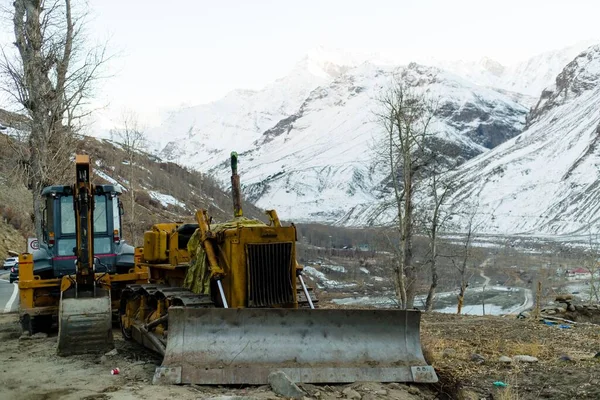 Bir Buldozer Traktör Arka Planda Karlı Dağlar Olan Kurak Ağaçların — Stok fotoğraf