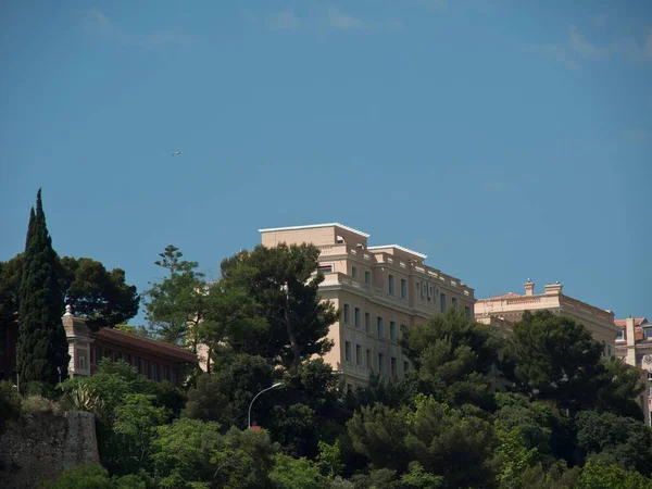 A big building behind green trees under blue sky