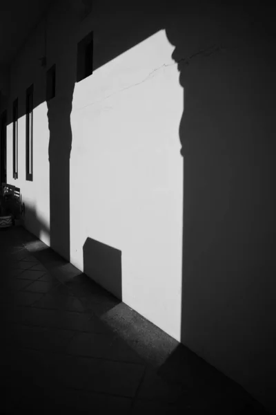 歩道に沿って壁の垂直グレースケールショット 日没時に柱の影と — ストック写真