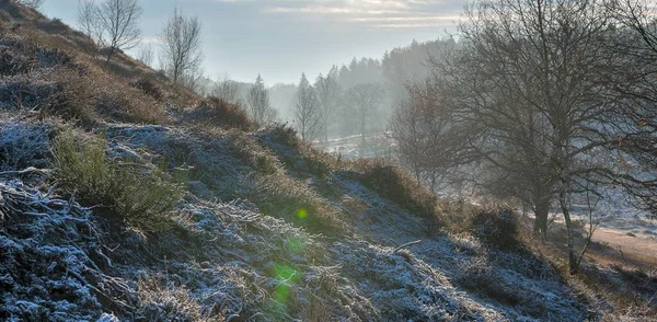 在阳光灿烂的天空下 一座覆盖着雪和草的小山的斜坡 — 图库照片