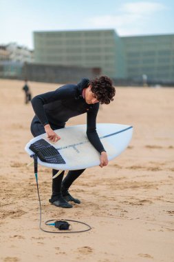 Beyaz bir erkek sörfçü okyanusta sörf yapmaya hazırlanıyor.