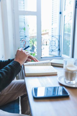 Deftere yazı yazan genç adamın elleri ve ahşap masa üzerinde kahve.