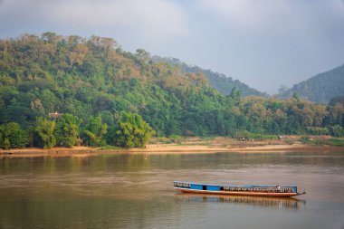 Luang Prabang, Laos 'taki dağların yakınında yüzen bir tekneyle Mekong Nehri' nin güzel bir görüntüsü.