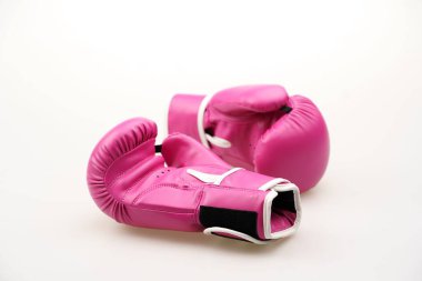 Beyaz arka planda izole edilmiş pembe boks eldivenlerinin yakın plan çekimi.
