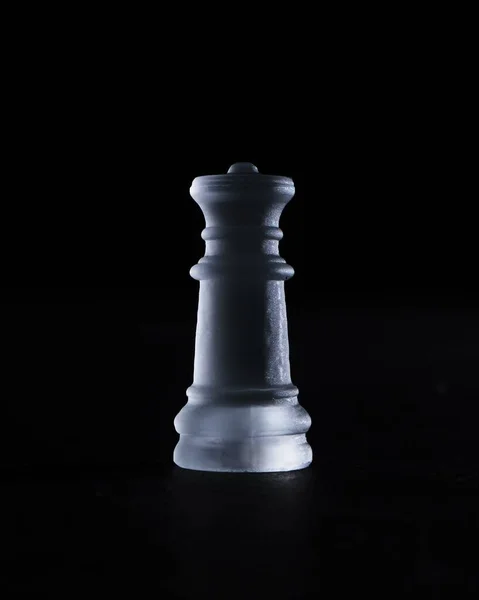 A vertical shot of a crystal queen chess piece isolated on a black background