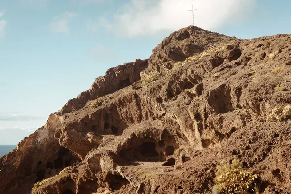 stock image A low angle of a cross on top of caves against the blue sky in Canary islands