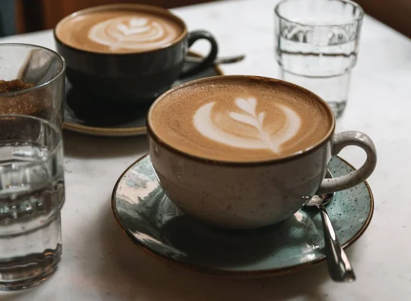 Närbild Två Koppar Cappuccino Med Latte Konst Ett Bord Ett — Stockfoto