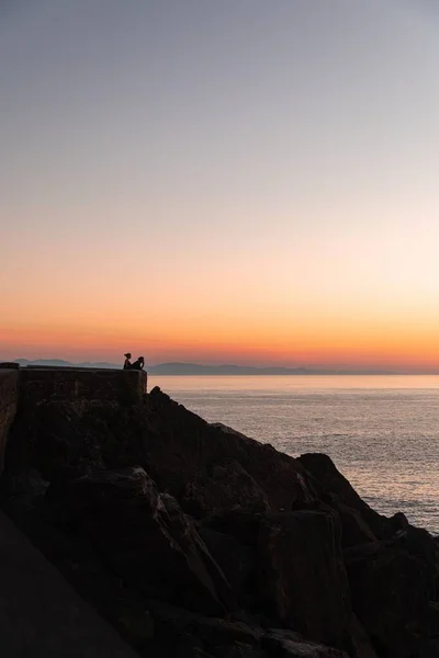 日落时一对夫妇在海岸上的垂直镜头 — 图库照片
