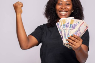 Heyecanlı Afrikalı kadın elinde para tutuyor.