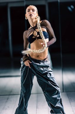 Dans stüdyosunda aynanın önünde poz veren çekici bir kızın dikey görüntüsü.