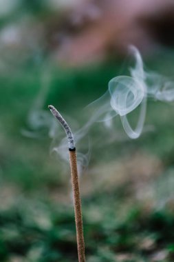 Bulanık bir arkaplanda yanan bir tütsü çubuğunun yakın çekimi