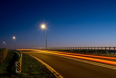 Alacakaranlık mavisi gökyüzü ile boş bir yolda trafik ışığı izleri