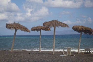 Güneşli bir günde saman şemsiyeli bir sahil.