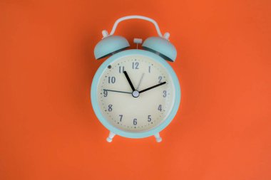 Turuncu bir arka planda mavi bir çalar saat. Zaman kavramı.