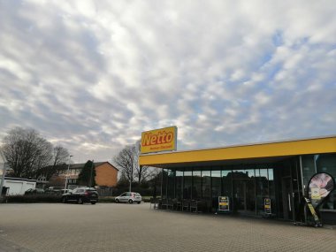 Netto Marken indirim süpermarketinin ön cephesi ve bulutlu gökyüzünün altındaki otopark