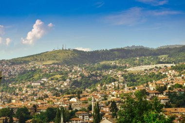 Saraybosna başkentinin ağaçlarla çevrili konut binalarıyla çekilmiş bir fotoğrafı.