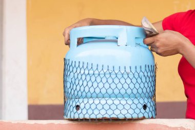 Kadın para tutuyor ve gaz tüpünü kaldırıyor.