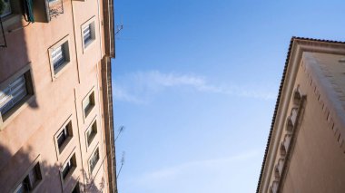 Güneşin altındaki mavi gökyüzüne karşı eski binaların çatısının alçak açısı.