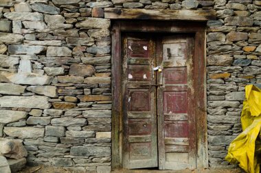 İtalyan kırsalında taştan bir kulübede kırsal ahşap bir kırmızı kapı.