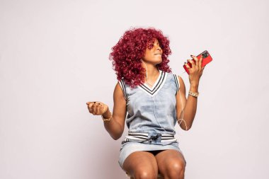 Müzik dinleyen güzel, genç, siyah bir kadın.