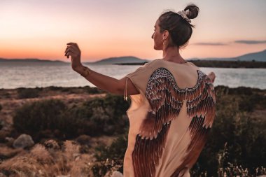 Beyaz bir kadın sahilde güzel bir gün batımının tadını çıkarıyor.