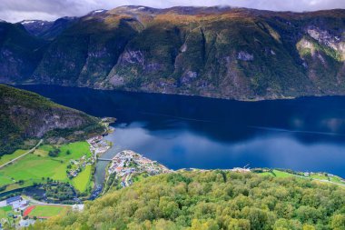 Kırsal kesimde gün ışığında büyük dağlarla çevrili mavi bir nehrin havadan görünüşü.